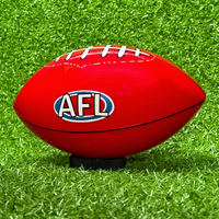Sports Gender Reveal AFL Ball - Red Australian football with AFL logo resting on vibrant green grass, positioned on a black display stand, perfect for gender reveal celebrations and sporting announcements.